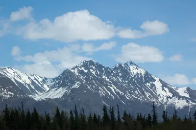 A close-up view of snow-covered mountain peaks under a clear blue sky in Alaska.