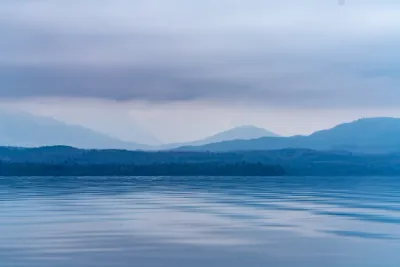 A soft, misty landscape of layers of blue hills and mountains under a low-hanging cloud bank in Alaska.