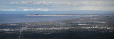 A distant view of Fire Island and its wind turbines from Anchorage across Cook Inlet, with the Alaska Range visible on the horizon.