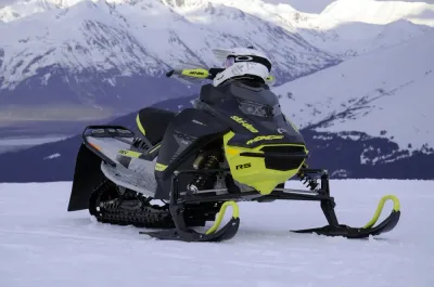 A close-up of a high-performance Ski-Doo snowmobile sitting on a snowy ridge.