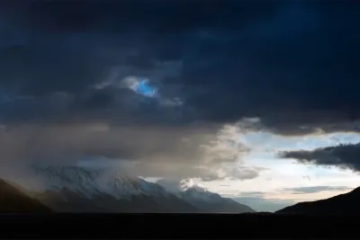 A moody, atmospheric view of the snow-covered mountains along Turnagain Arm in Alaska.