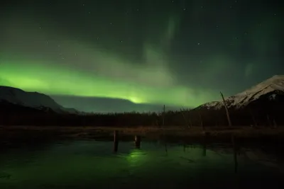 A diffused green aurora glow over an icy lake with a slightly different auroral configuration.